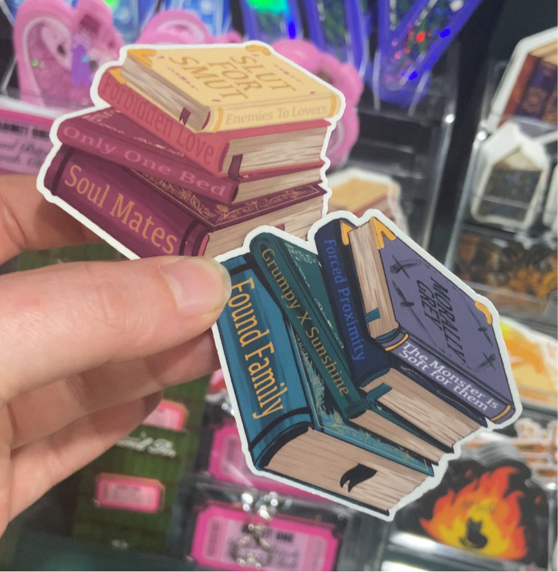 Stack of book-shaped stickers with text held by a hand against a colorful background.