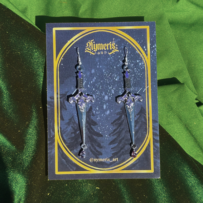 Sword-shaped earrings on a branded card with a green fabric background