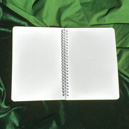 Open notebook with grid paper on a green fabric background