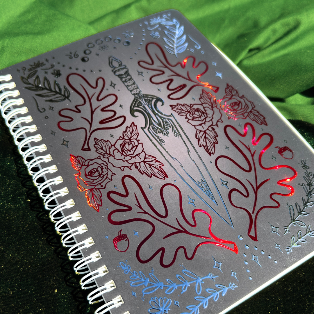 Notebook with decorative sword and leaf design on a green fabric background