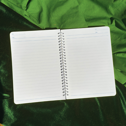 Open spiral-bound notebook on a green fabric background