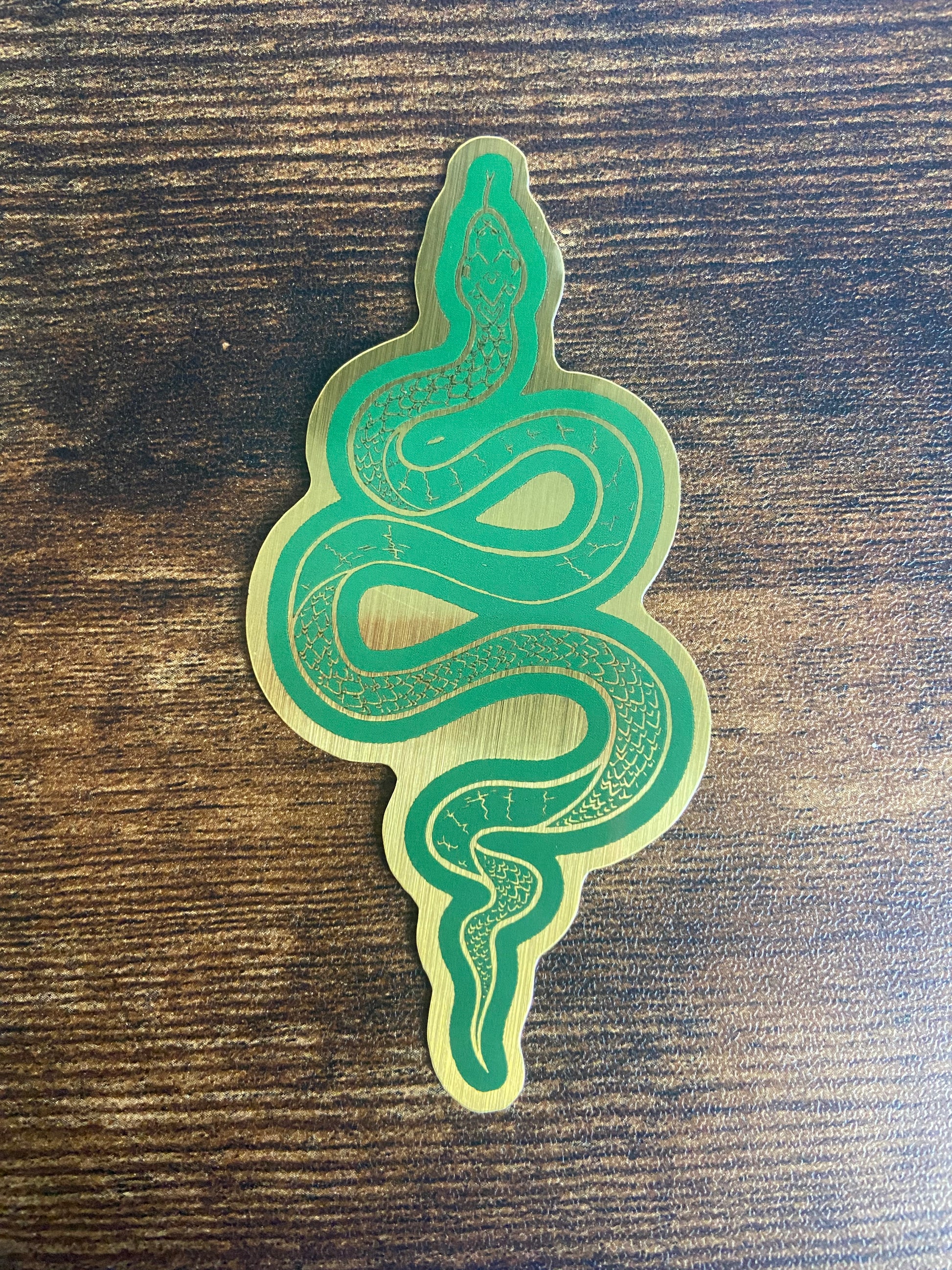 Green snake-shaped sticker on a wooden surface