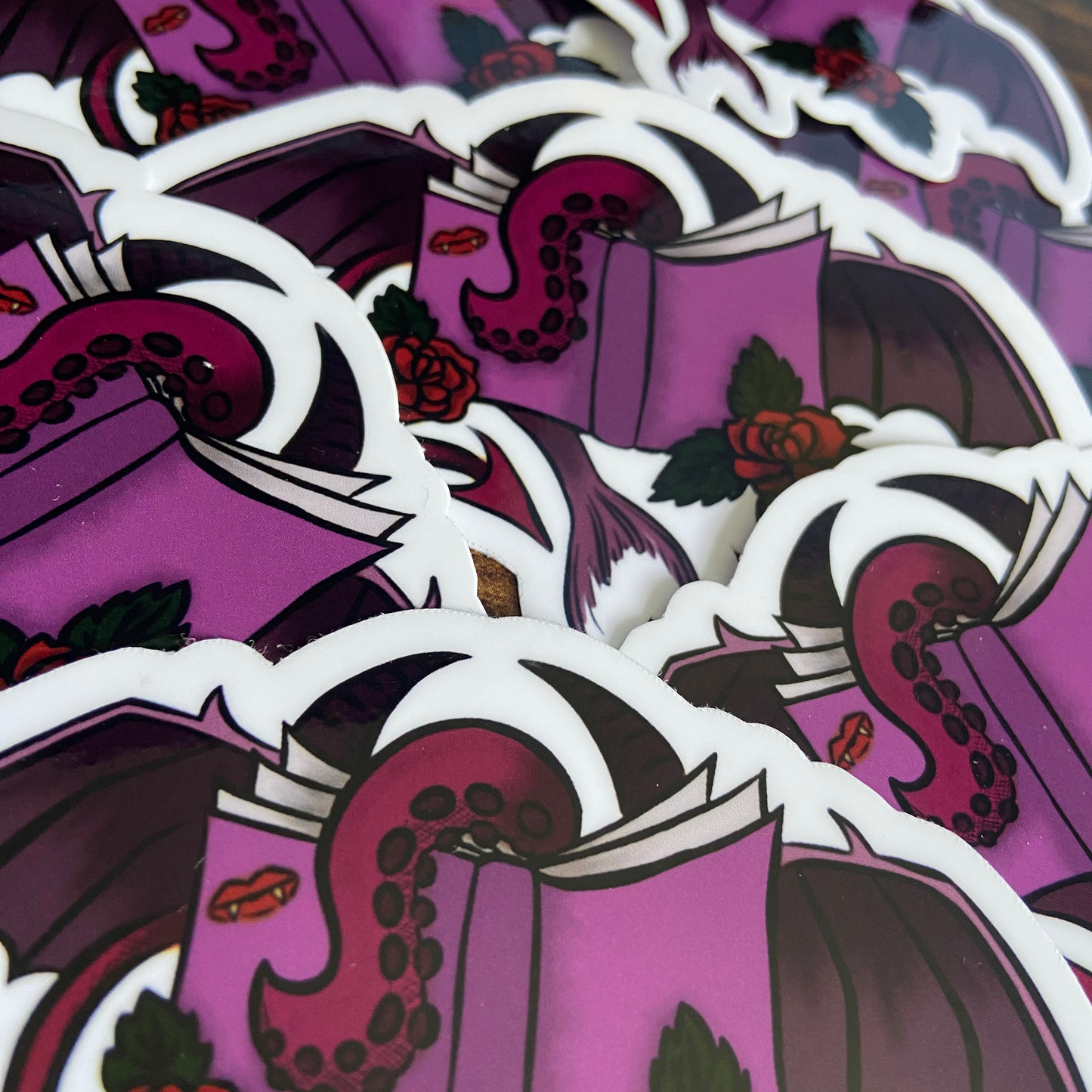 Stack of stickers with a purple book and dragon design on a wooden surface.