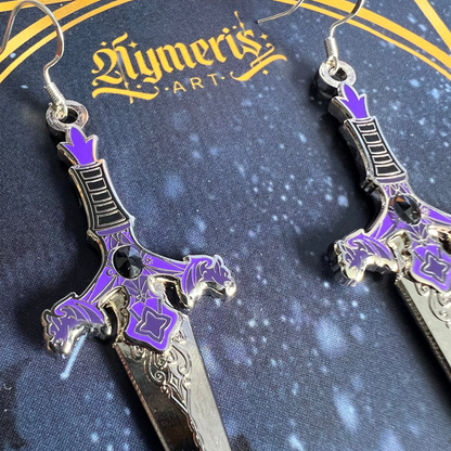 Sword-shaped gargoyle earrings with purple accents on a dark blue background with 'Nymeris Art' branding.